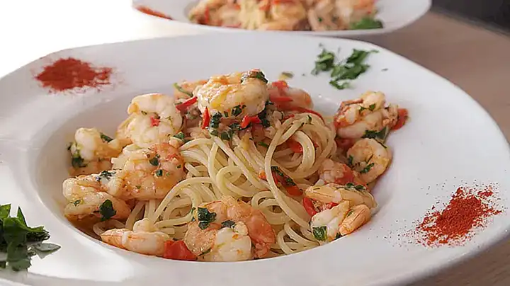 Sirve los camarones al ajillo sobre una cama de pasta al dente
